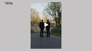 Kanzler Merz und Minister Klingbeil stehen vor einem Teich.