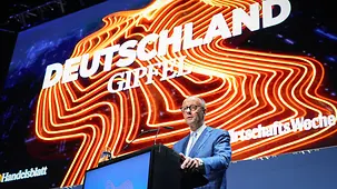 Bundeskanzler Friedrich Merz am Pult auf der Bühne, während er eine Rede hält.
