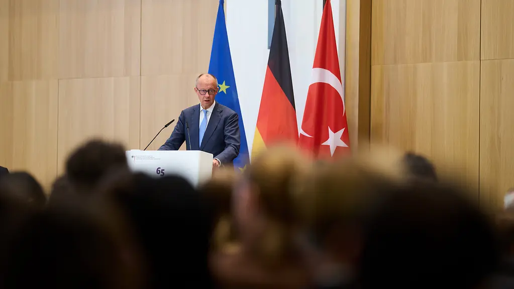 Bundeskanzler Merz steht hinter einem Pult. Hinter ihm sind die deutsche, türkische und europäische Flagge zu sehen. 