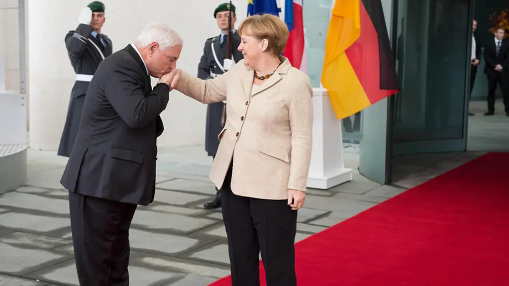 Ricardo Martinelli kisses Angela Merkel's hand.