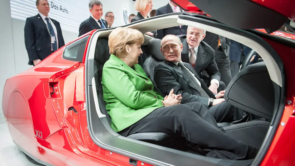 Angela Merkel and Vladimir Putin take their seats in the Volkswagen XL1.
