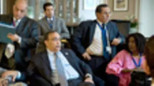 A group of delegates discuss the situation in the hotel lobby.