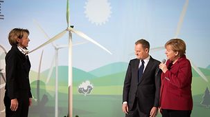 Angela Merkel and Donald Tusk in front of the photo of a wind turbine