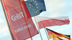 The Polish, EU, German and CeBIT flags fly against a blue sky.