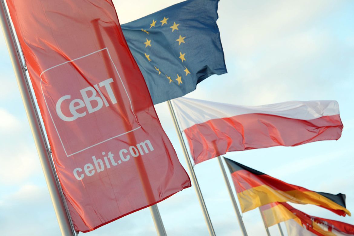 The Polish, EU, German and CeBIT flags fly against a blue sky.