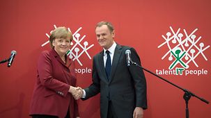 Angela Merkel and Donald Tusk shake hands.