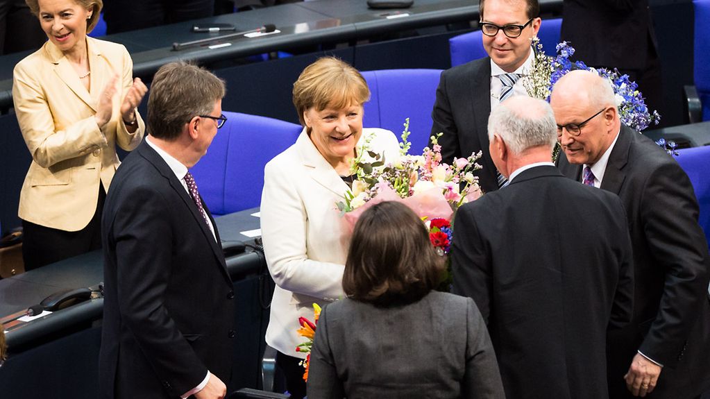 Bundes-Kanzlerin Angela Merkel bekommt Blumensträuße.