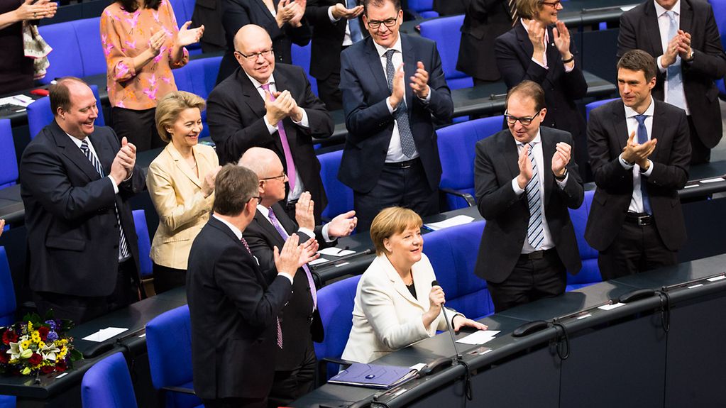 Abgeordnete applaudieren Bundes-Kanzlerin Angela Merkel.